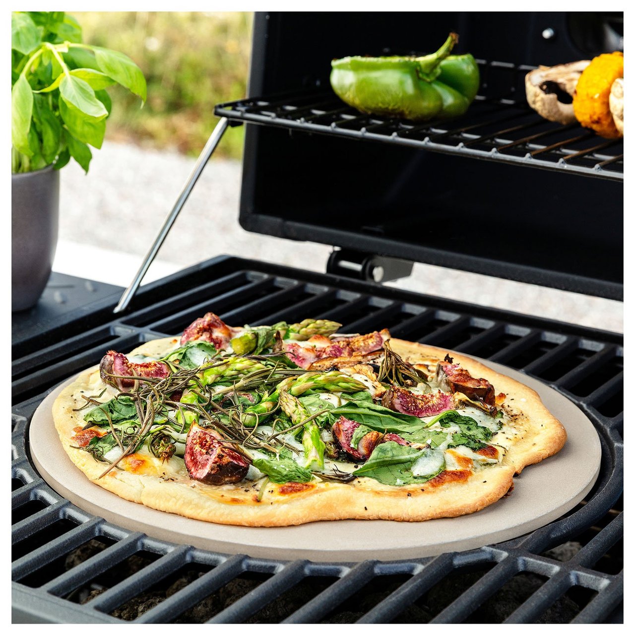Pizza, die mit einem Pizzastein auf einem Gasgrill zubereitet wird.