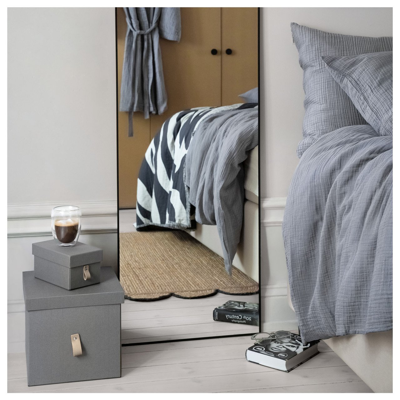 Veggspeil stående på gulvet i et soverom.