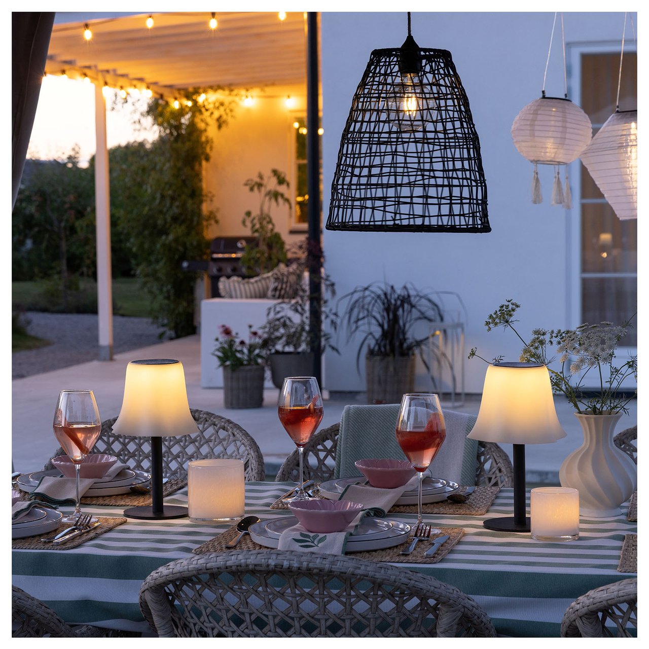 Ett dukat bord med bordslampor omges av hängande lampor och ljusslingor.