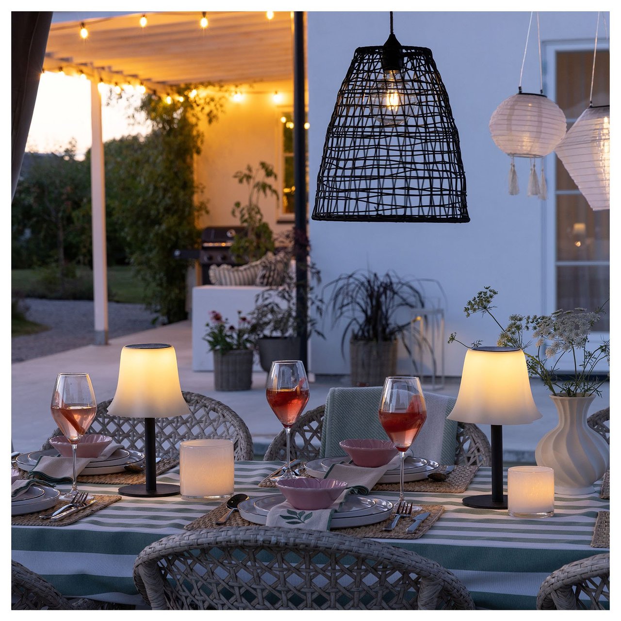 Ett dukat bord med bordslampor omges av hängande lampor och ljusslingor.