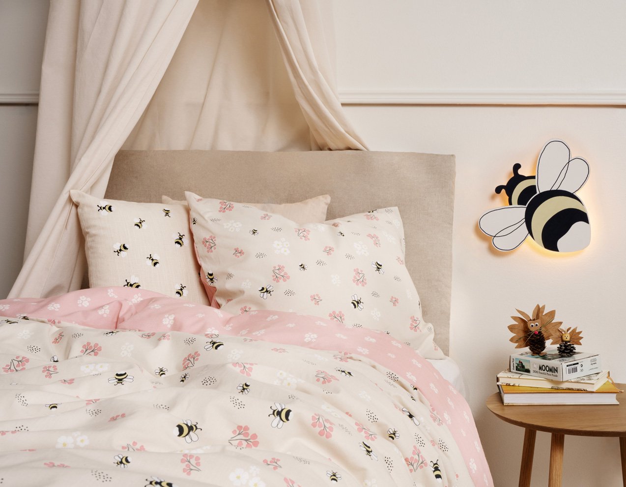 Barnsäng med lekfullt bäddset och nattlampa i form av ett bi.