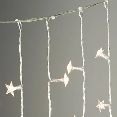 Nahaufnahme eines hängenden Lichtervorhangs mit kleinen sternförmigen Lampen.
