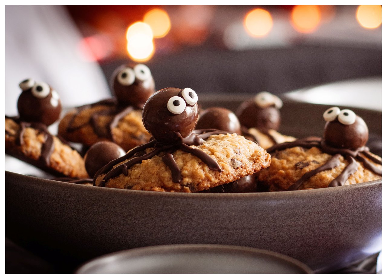 Schokokekse, dekoriert mit Augen wie Spinnen in einer Schale in Halloweenatmosphäre.