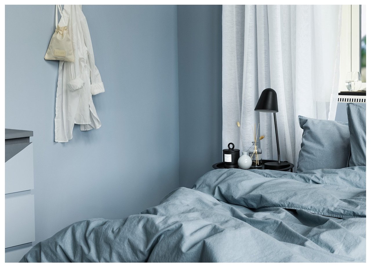 Sisustusinspiraatiota makuuhuoneesta, jossa on sijattu sänky, sivupöytä ja tummansinisen sävyinen seinä.