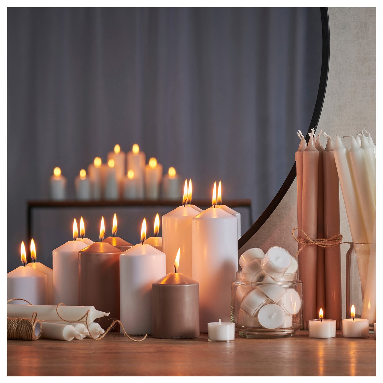 Verschiedene Formen von Kerzen und Teelichtern sind auf einem Tisch aufgereiht.