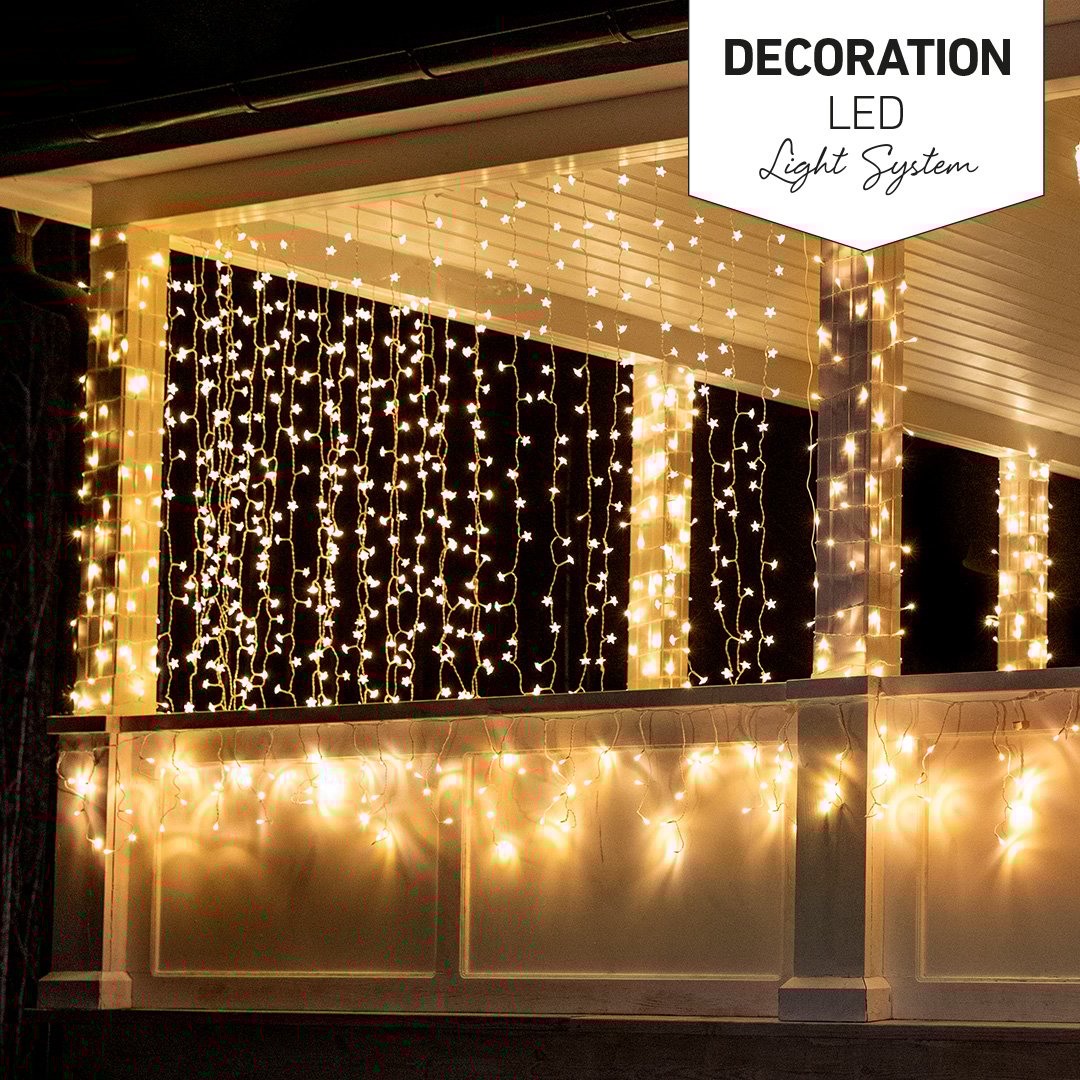 Husveranda dekorerad med ljusslingor och julgran i kvällsbelysning, Decoration LED Light System-logga.