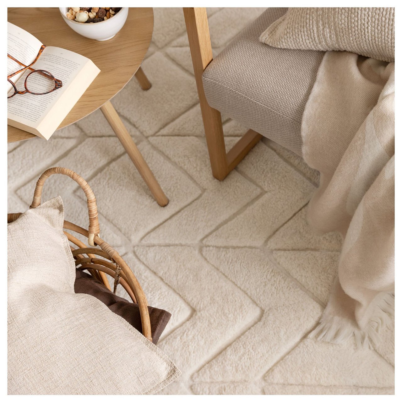 Naturweißer Tuftingteppich. Stuhl mit beigefarbenem Kissen und Decke.