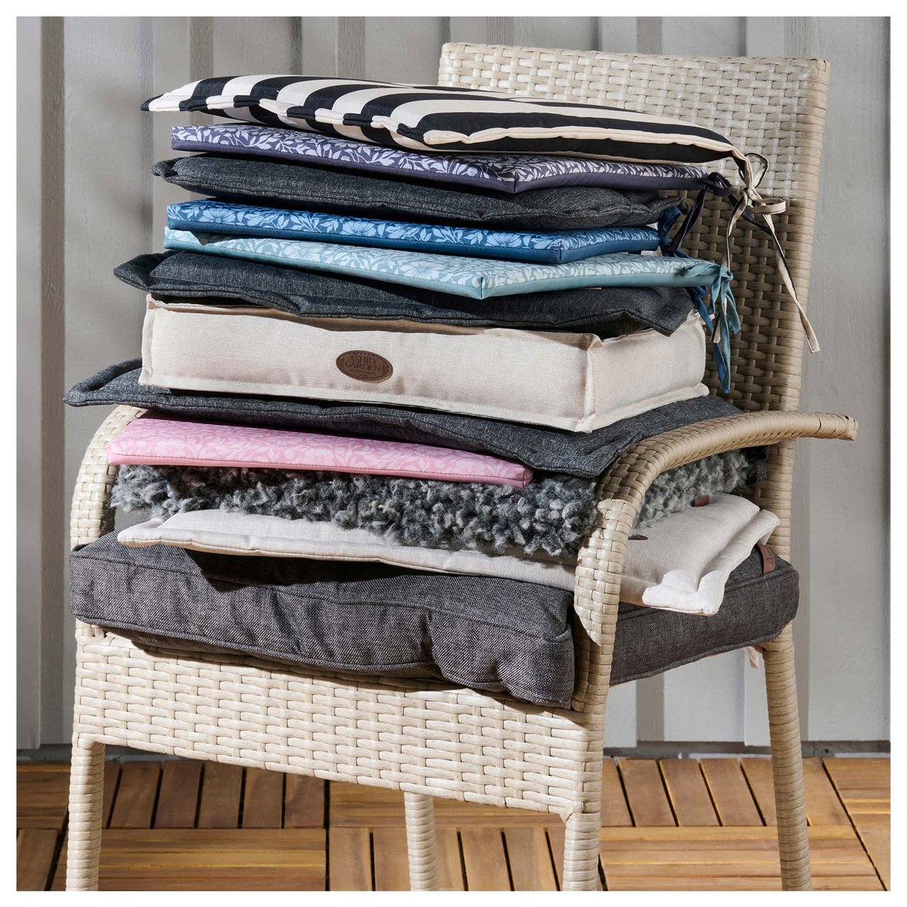 Beige rottingstol med masse sitteputer i forskjellige farger.