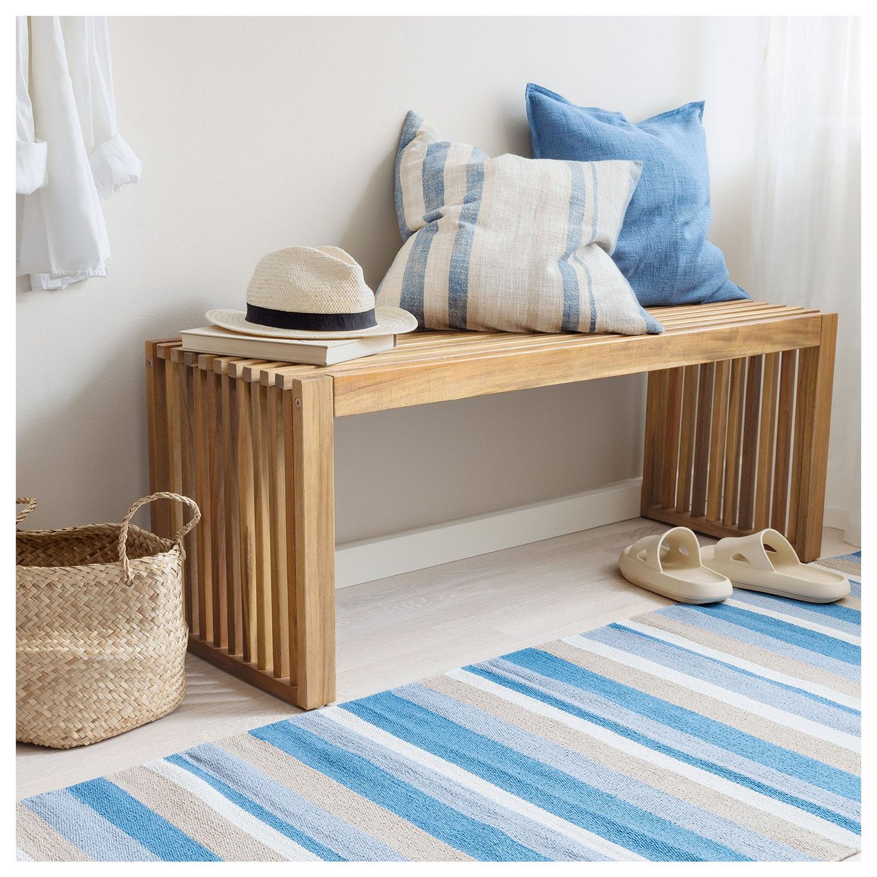 En blåvitrandig gångmatta framför en träbänk med kuddar i blått.