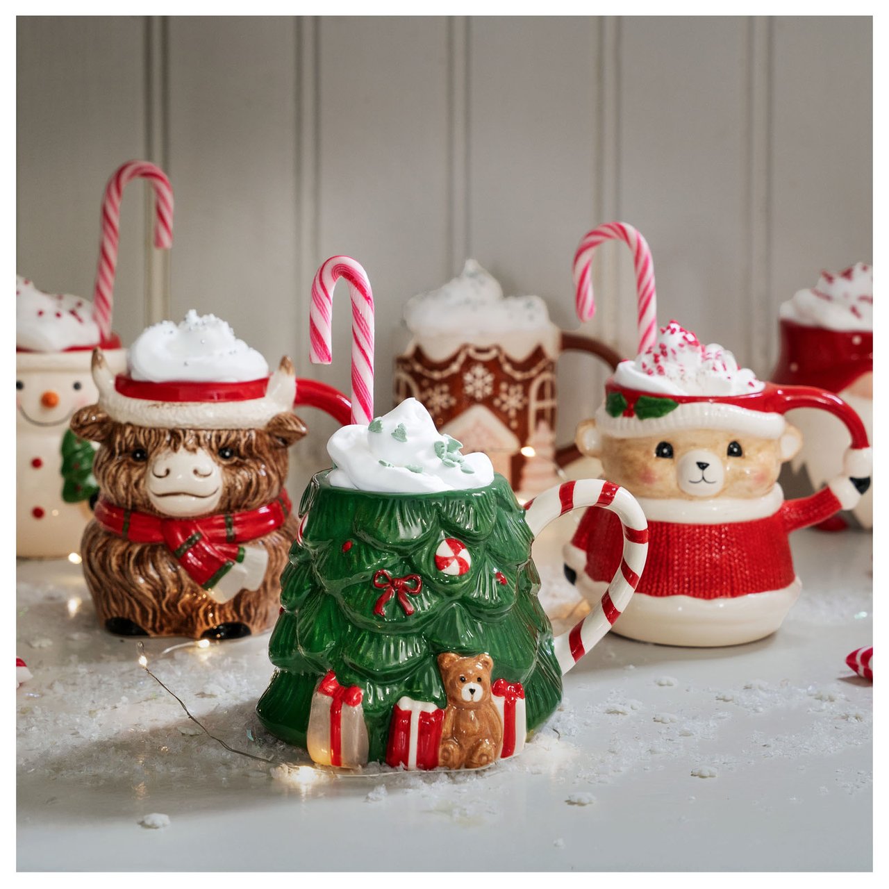 Värikkäitä joulumukeja, täytettynä lämpimällä juomalla ja koristeltuna kermavaahdolla ja polkakarkeilla.