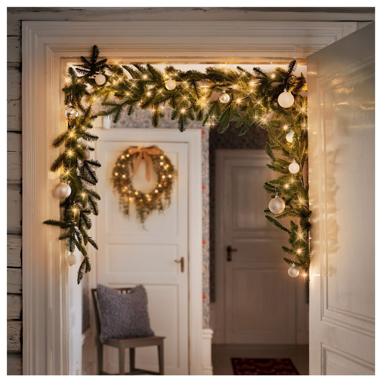 Türöffnung mit Lichterkette und Tannengirlande geschmückt.