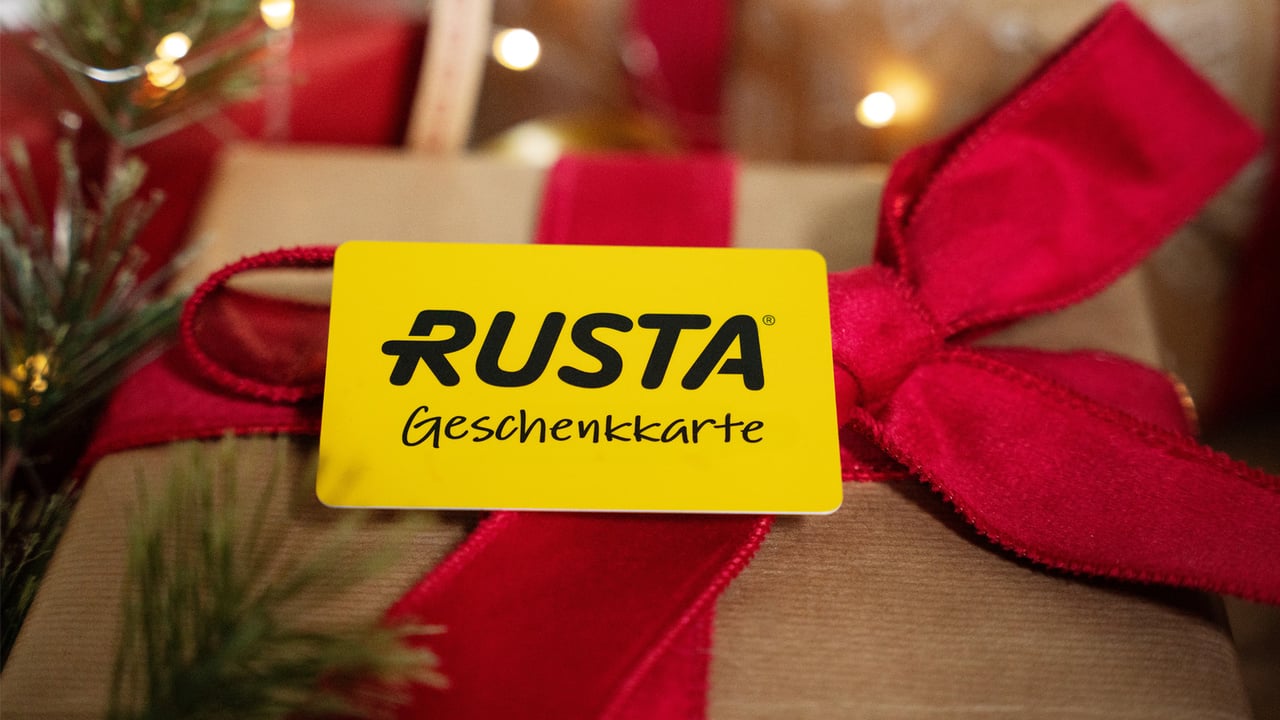 Eine Rusta-Geschenkkarte, die auf einem Weihnachtsgeschenk liegt.