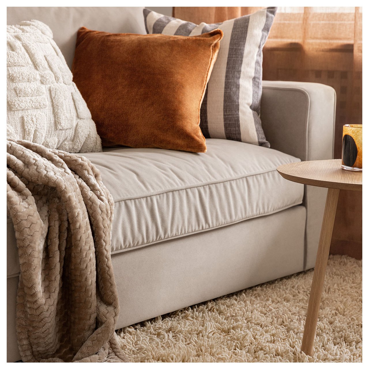 Graues Sofa mit Zierkissen auf einem langflorigen Teppich.