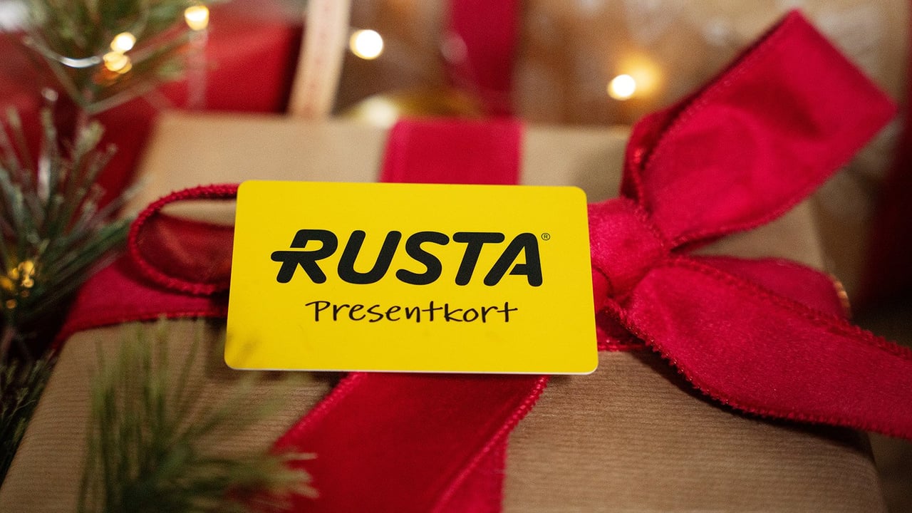 Julklapp inslagen med röda presentband och ett gult presentkort från Rusta.