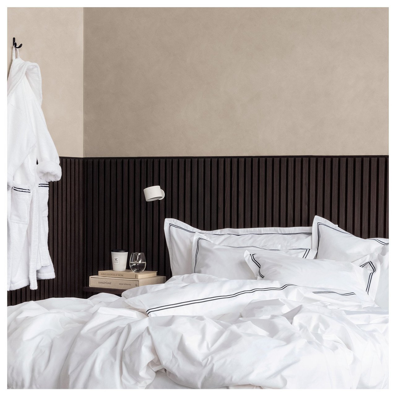 Sovrum med beige väggfärg och mörk akustikpanel.