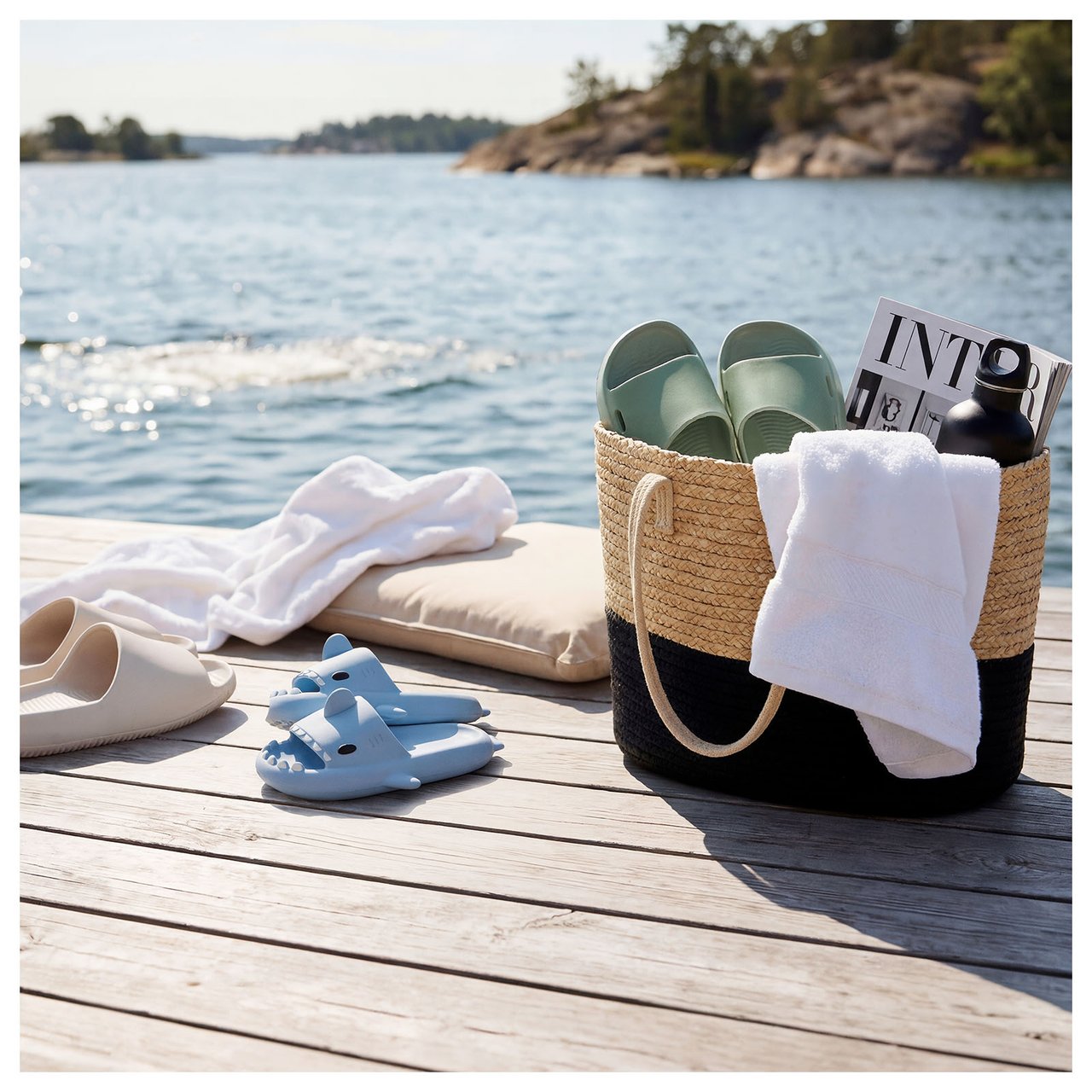 En person med stråhatt og en praktisk kjøleryggsekk ser ut over et vann, klar for en herlig utflukt med vannflaske og pikniktilbehør.