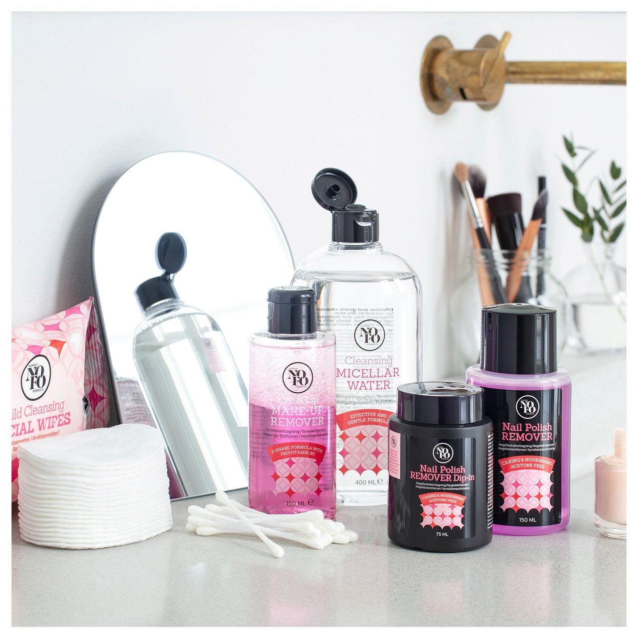 Sminkborttagningsprodukter, spegel och bomullstillbehör uppställda på badrumshylla.