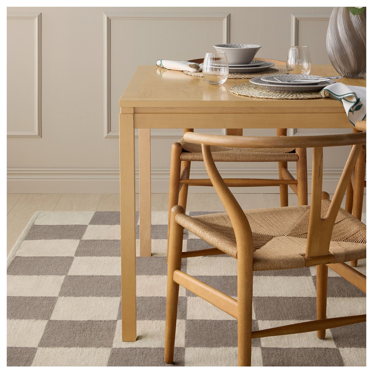 En schackmönstrad matta i beige och grått under ett matbord. 