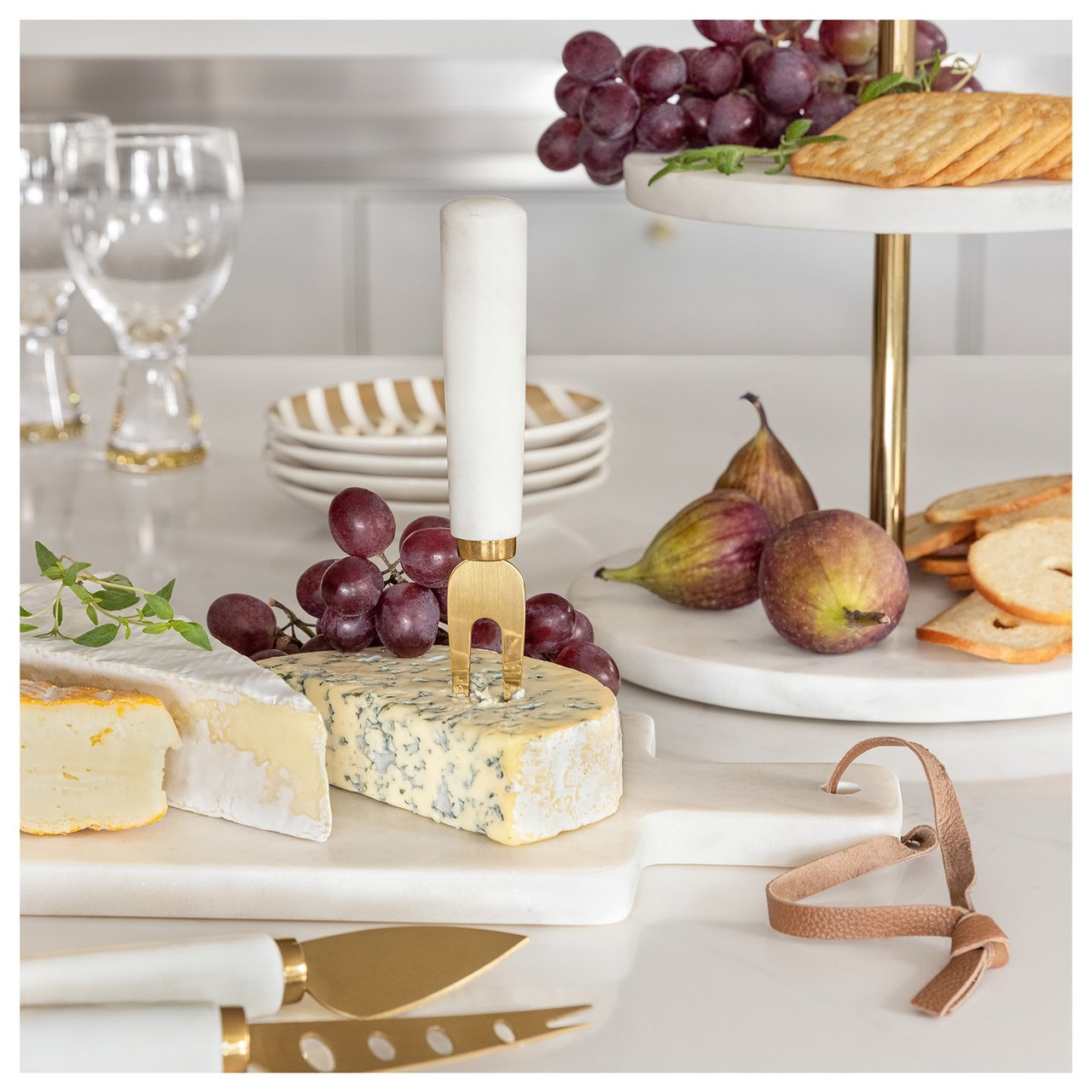 Käse und Cracker auf einem Schneidebrett und einer Etagere aus Marmor.