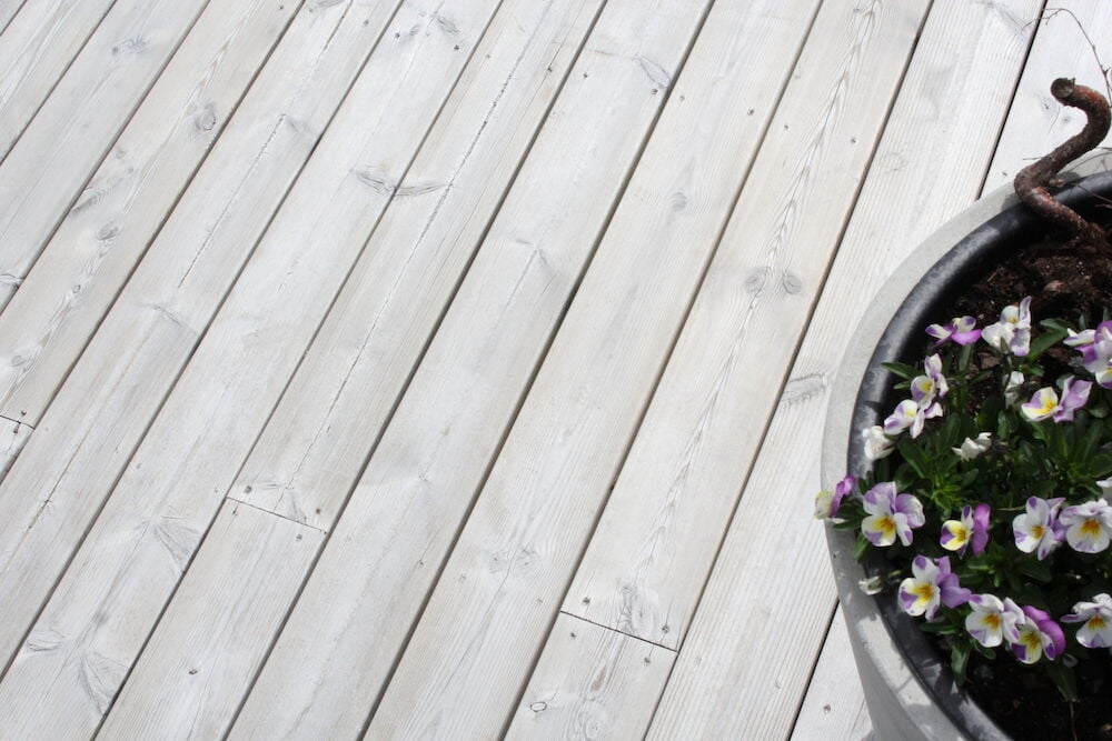Ljust trätrall utomhus med blomkruka och blommor.