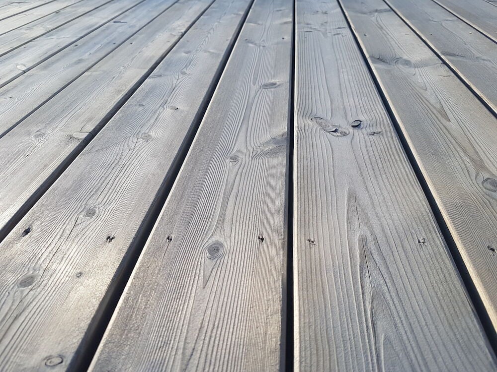 Silvergrå altan med behandlat trä och tydliga träådror.