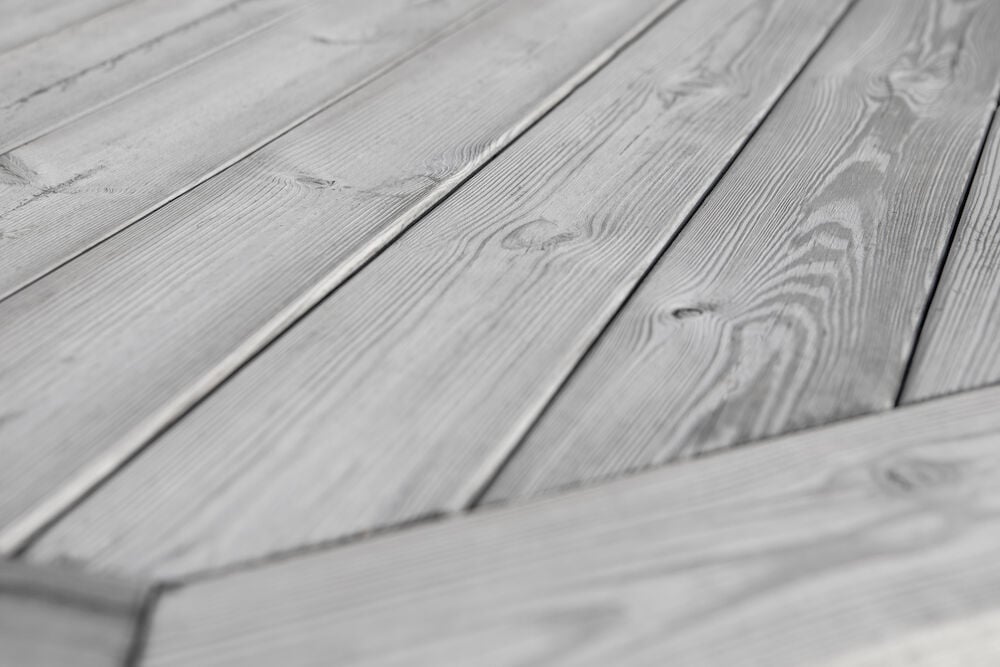 Silvergrå altan med slät och len träyta.