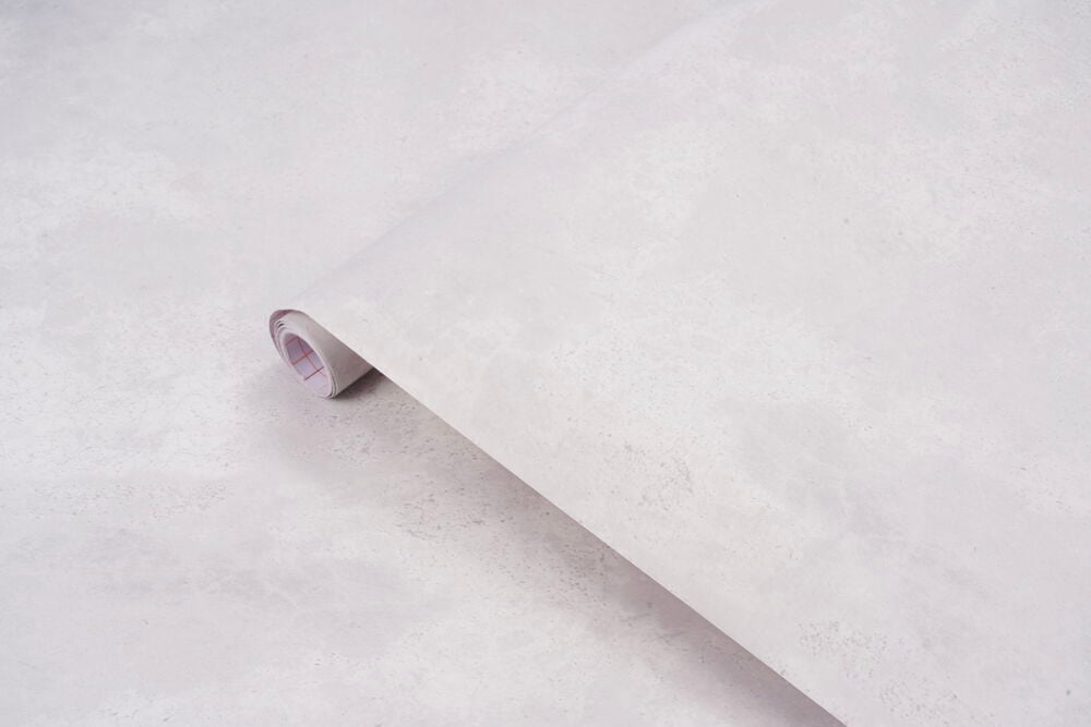 Lys grå teksturert Dekorplast 200x67,5 cm rull delvis rullet ut på matchende overflate, viser bakpapir.