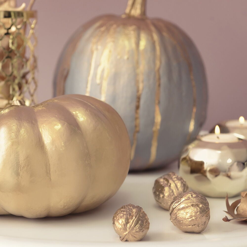 Kullalla lakatut kurpitsat ja pähkinät koristeina.