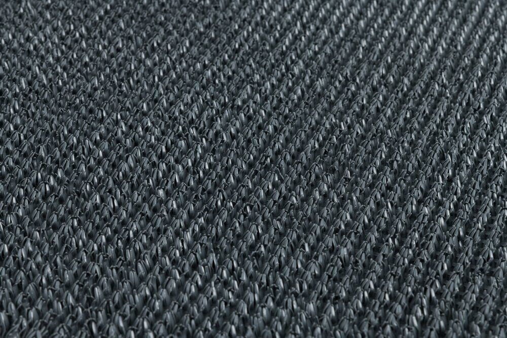 Lähikuva mustasta kudotusta muovimatosta, jossa on rakenne.
