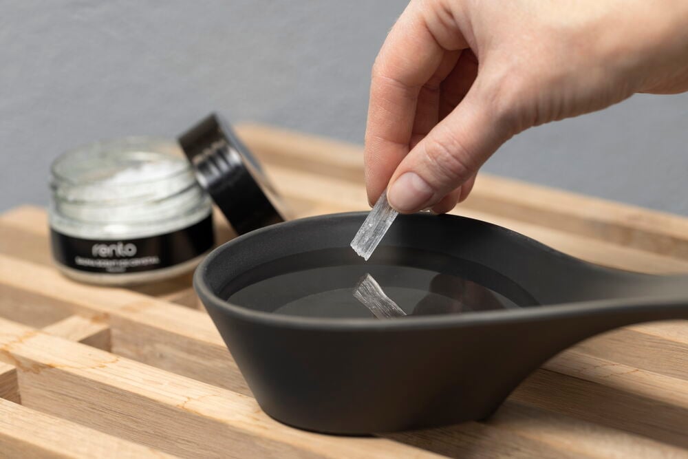 Hän asettaa kristallin veteen mustaan kulhoon.