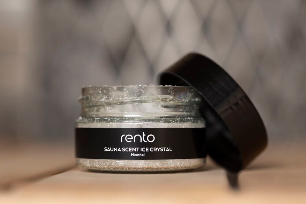 Avoin lasipurkki, jossa on läpinäkyviä mentolikiteitä ja musta kansi.