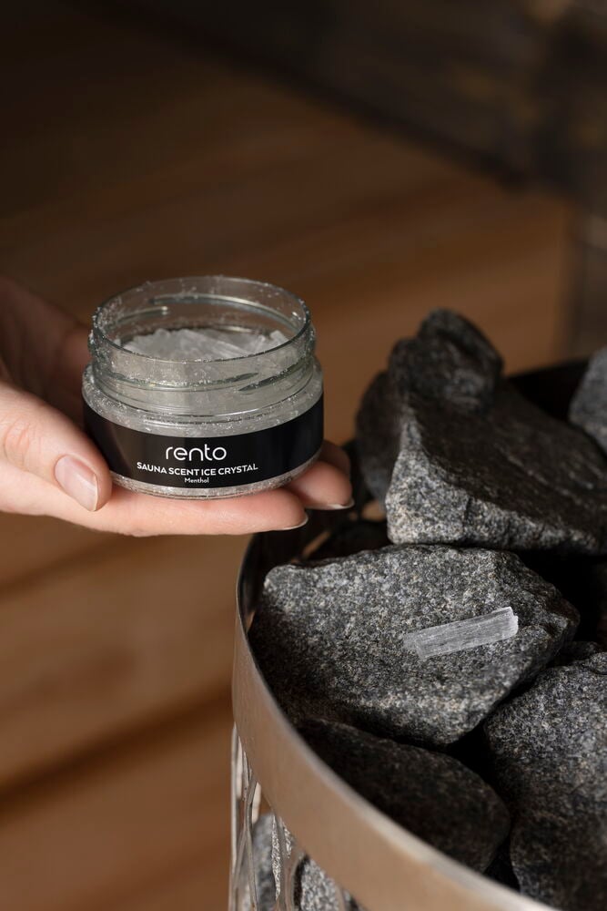 Käsi pitää mentolikristalleja sisältävää purkkia kiukaalla.