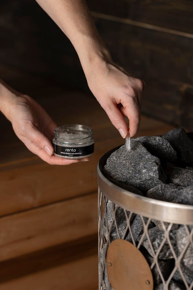 Käsi asettaa mentolikiteen saunankiville.