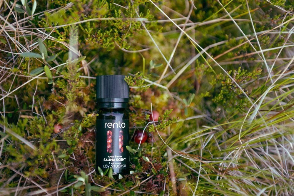 Musta pullo saunantuoksua vihreällä sammaleella ulkona.