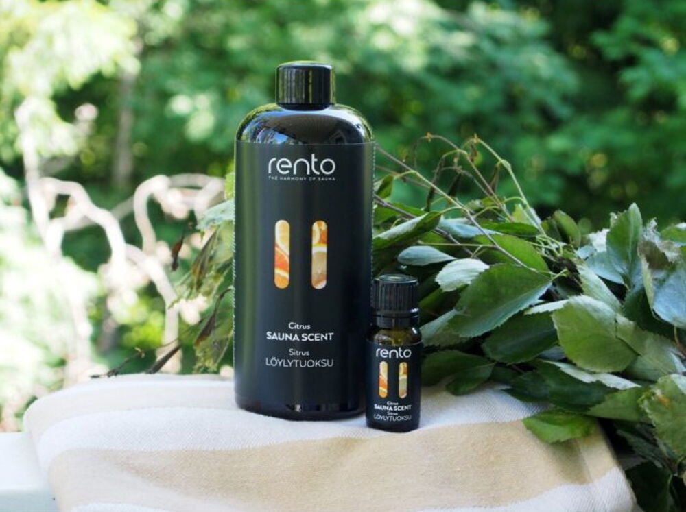 Kaksi mustaa pulloa saunatuoksua pyyhkeellä ulkona.