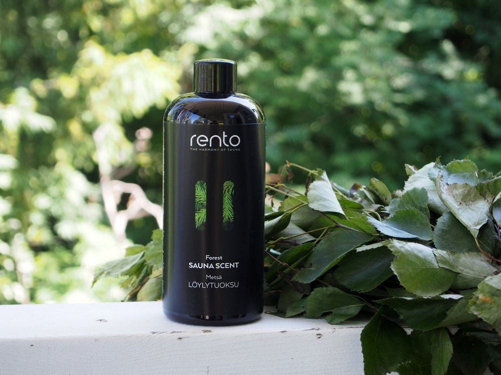 Musta pullo saunan tuoksua koivuvihan edessä ulkona.