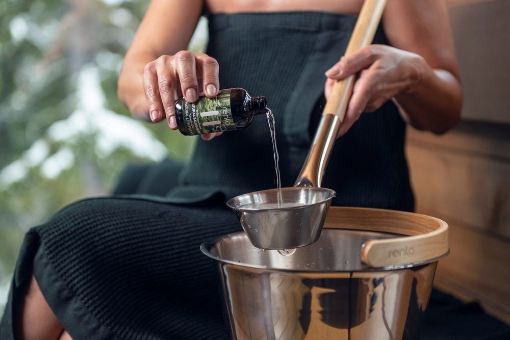 Nainen kaataa saunatuoksua kulhoon kauhalla.