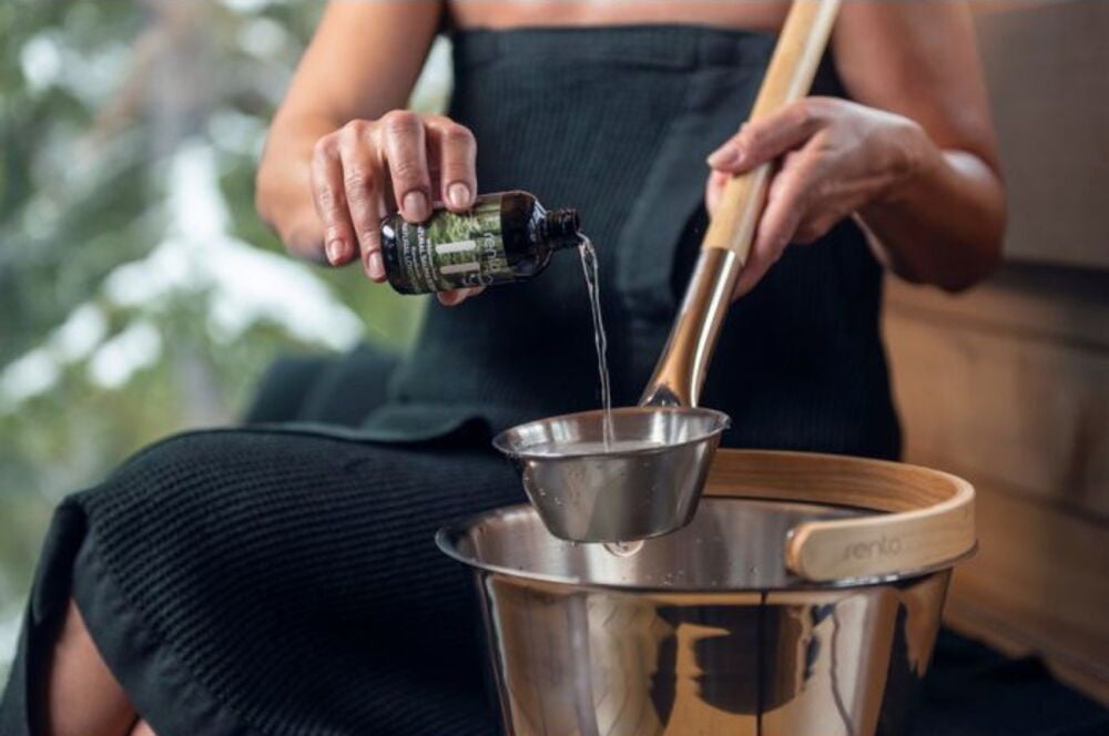 Henkilö kaataa saunatuoksua kulhoon puukauhalla.