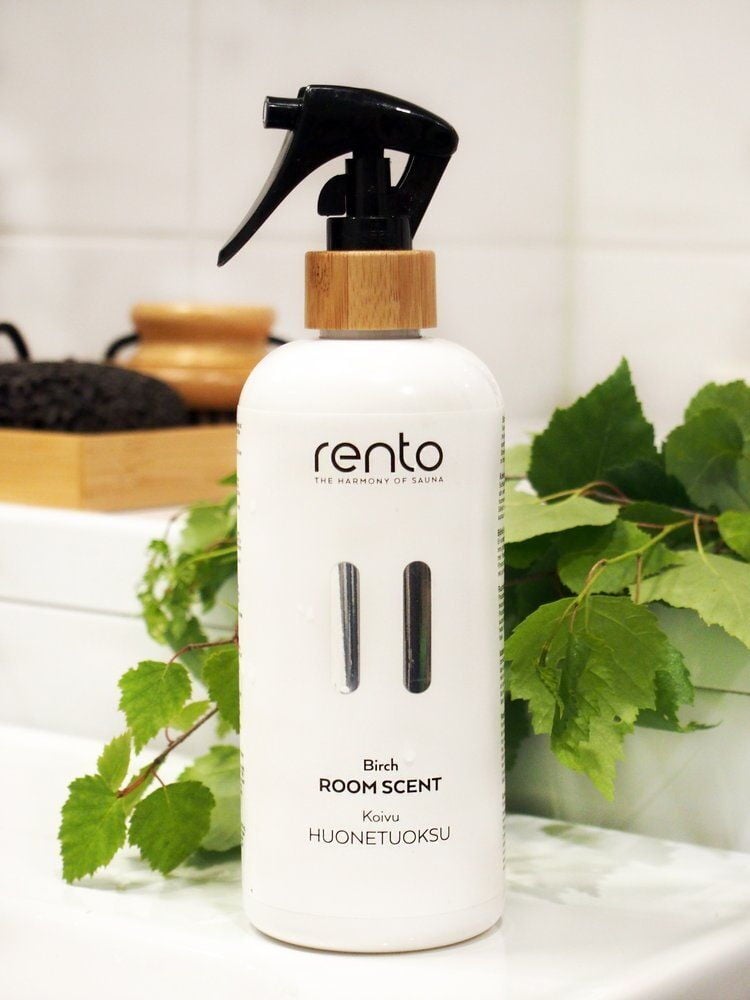 Valkoinen sumutepullo, jossa on koivuntuoksu vihreiden lehtien vieressä.