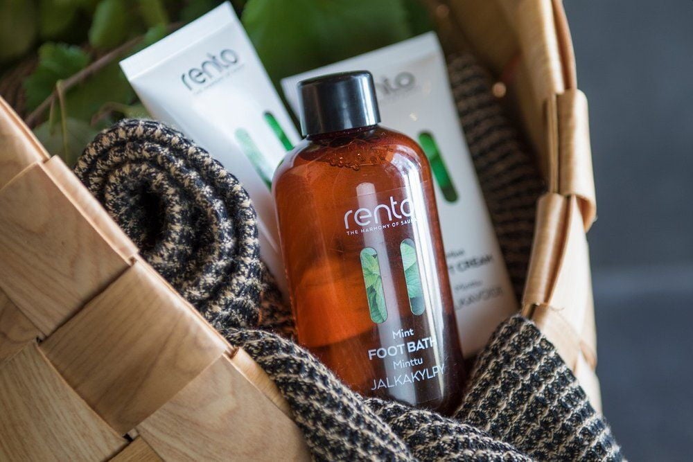 Ruskea muovipullo ja voideputket korissa pyyhkeen kanssa.