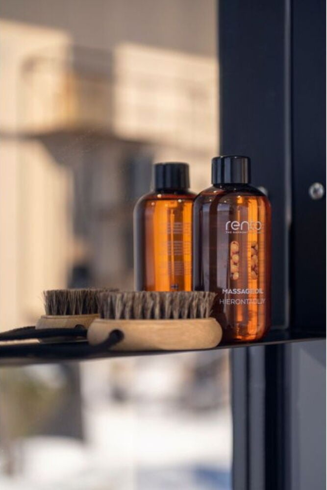 Kaksi ruskeaa hierontaöljypulloa harjasten vieressä.