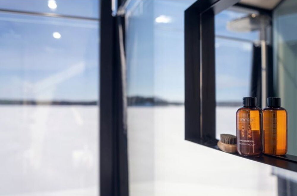 Kaksi ruskeaa pulloa hierontaöljyä mustalla hyllyllä.