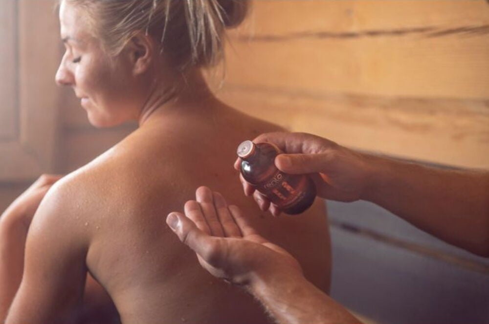 Henkilö levittää hierontaöljyä naisen paljaalle selälle.