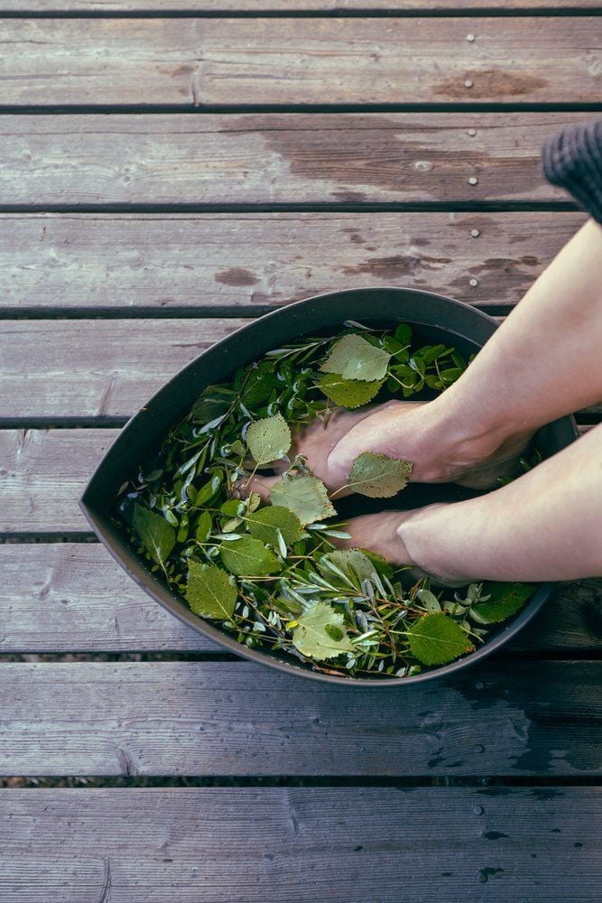 Jalat tummassa pisaranmuotoisessa altaassa vihreillä lehdillä.