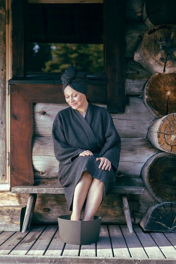 Nainen liottaa jalkojaan ruskeassa pesualtaassa ulkona.