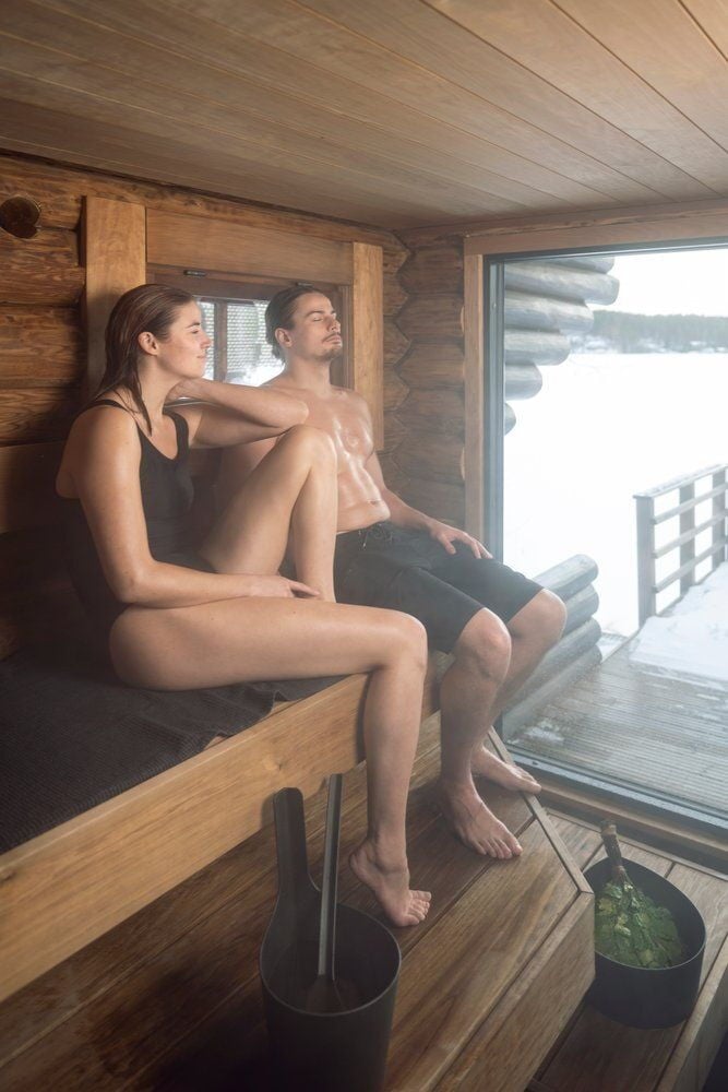 Kaksi henkilöä rentoutuu puusaunassa.