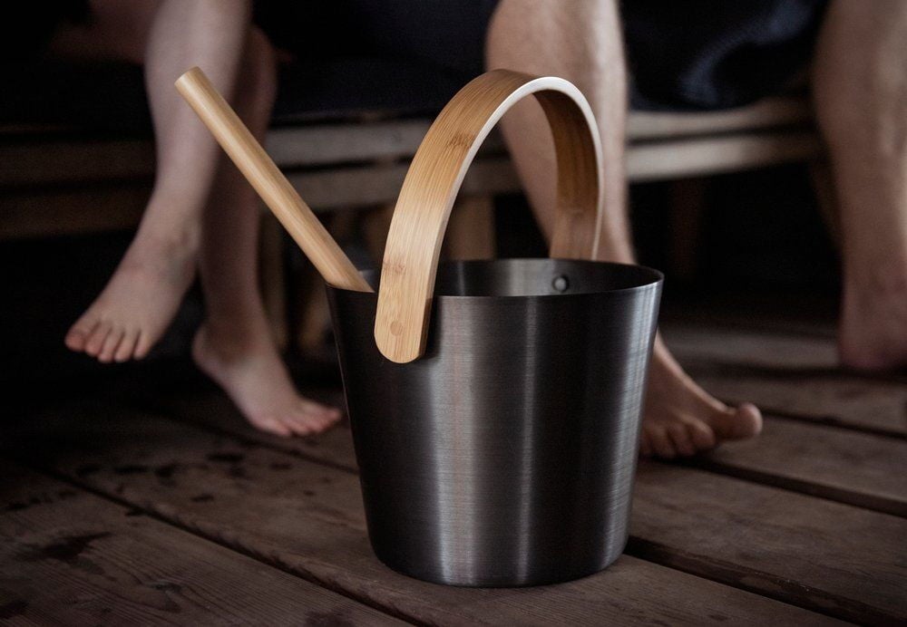 Musta saavi bambukahvalla ja siihen kuuluva kauha.