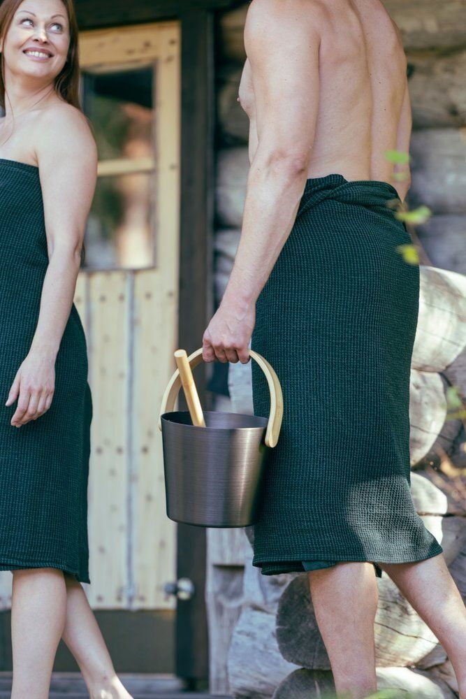 Mies kantaa mustaa saunakiulua, jossa on puukahva, ulkona.