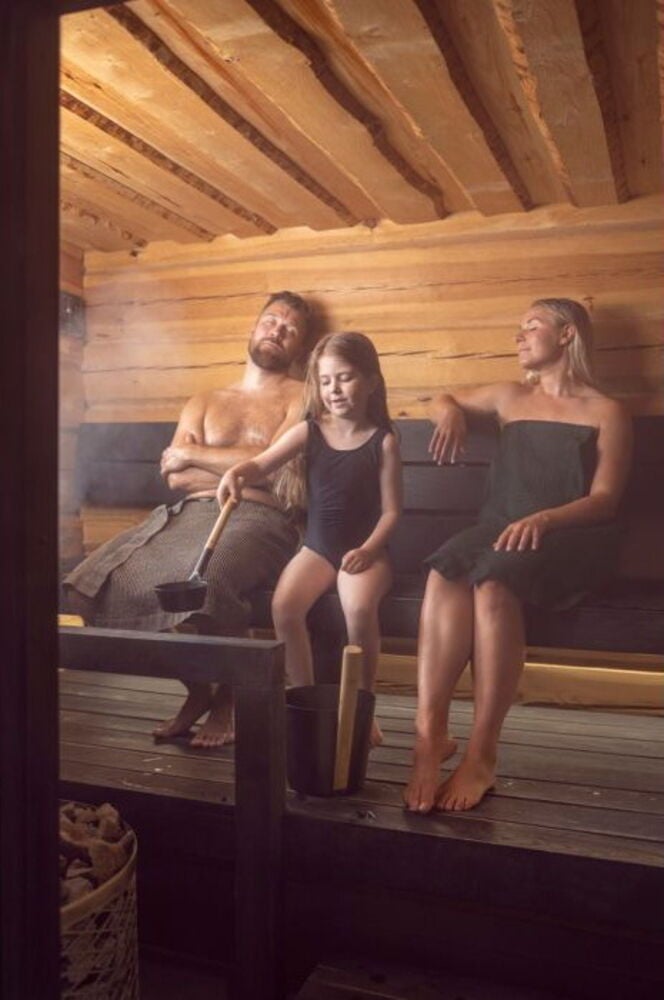 Tyttö käyttää mustakahvaista saunakauhaa saunassa.