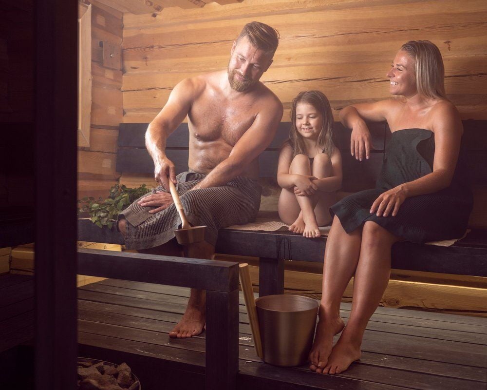Perhe saunassa saunakauhan ja saaviämpärin kanssa.